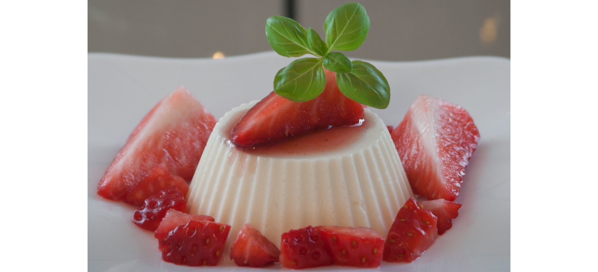 Zdjęcie przedstawia panna cottę z truskawkami.
