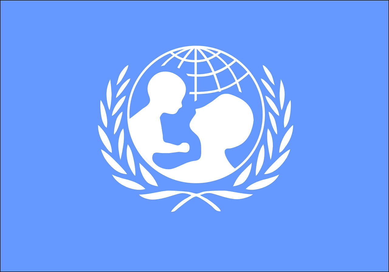 Logo UNICEF‑u przedstawia ikonę matki z dzieckiem, umieszczoną wewnątrz kuli ziemskiej i otoczoną gałązkami oliwnymi.
