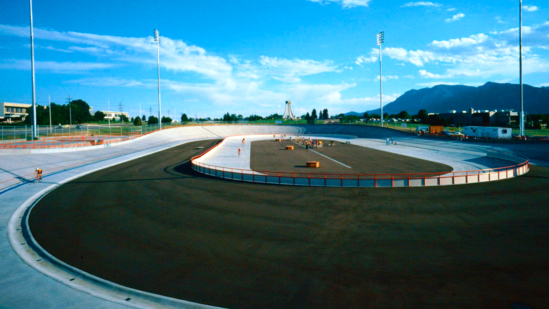 Zdjęcie przedstawia widok na stadion kolarski. Na stadionie widoczny jest tor, na którym ścigają się kolarze.