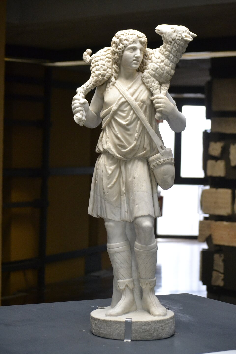 Marmurowa rzeźba przedstawia młodzieńczego Hermesa stojącego frontalnie, z baranem przerzuconym przez ramiona. Bóg ubrany jest w krótką tunikę i wysokie sandały; na piersi widoczny pas przewieszonej torby. Oburącz podtrzymuje zwierzę, którego głowa spoczywa przy jego lewym ramieniu. Twarz ma spokojny, skupiony wyraz, a kręcone włosy okalają głowę. Figura stoi na okrągłej podstawie w muzealnej sali.