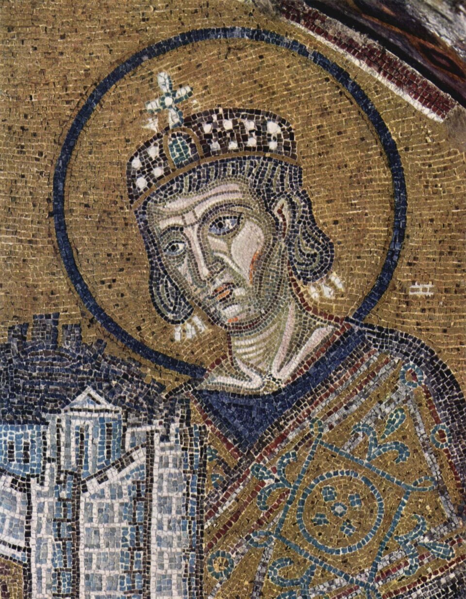 Fotografia przedstawia mozaikę w Hagia Sofia, jest to postać Konstantyna I Wielkiego z modelem miasta. Mężczyzna ubrany w szaty, ma nakrycie głowy z umocowanym krzyżem. Ma poważny, niewyraźny wyraz twarzy.