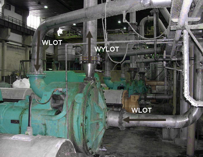 Zdjęcie przedstawia młyn tarczowy znajdujący się w zakładzie papierniczym. W bocznej części urządzenia znajduje się wlot, do którego została zamontowana rura. Drugi wlot mieści się w górnej części, podobnie jak wylot. Urządzenie jest podłączone do całego systemu rur transportujących masę.