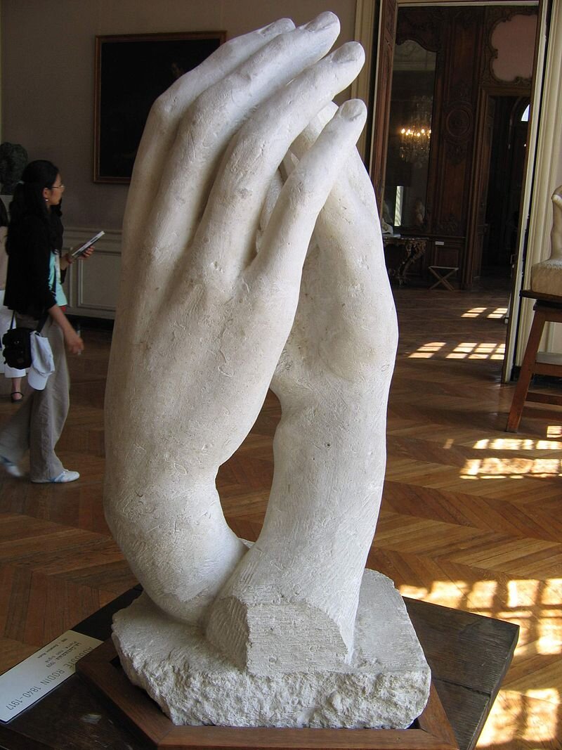 Ilustracja przedstawia rzeźbę dwóch splecionych dłoni jakby w tańcu. Dłonie wyglądają tak, jakby chroniły wewnątrz coś ulotnego i nieuchwytnego. Prawdopodobnie jedna należy do kobiety a druga do mężczyzny. Te dłonie ułożone są w kształt łuku.  Dwie dłonie mogą także niektórym przypominać dłonie złożone do modlitwy. Dłonie są umieszczone na marmurowym cokole.