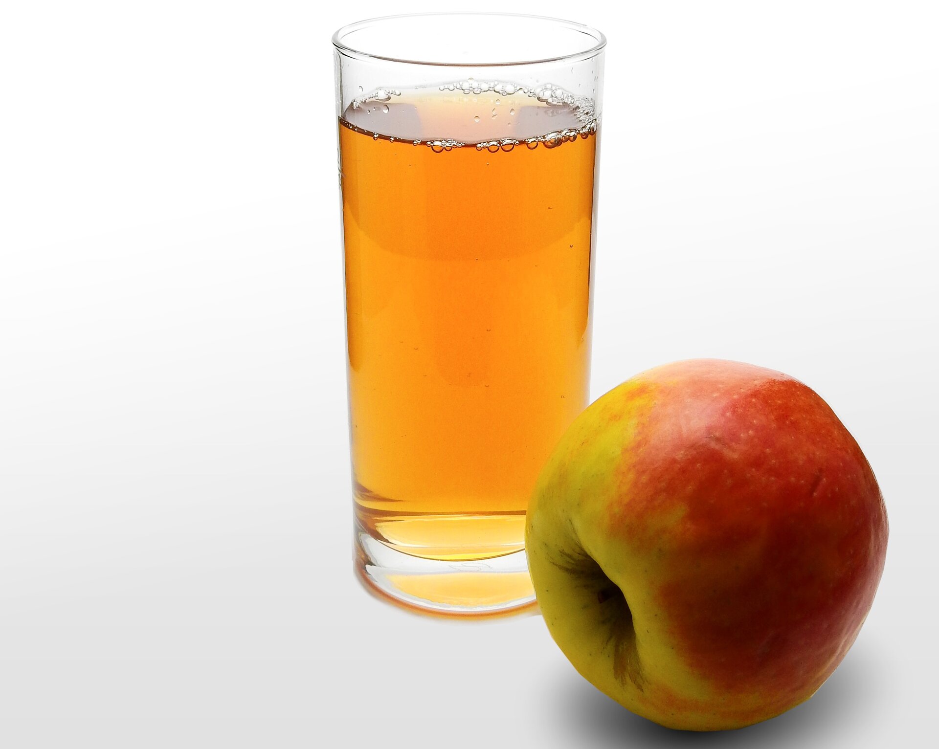 Ilustracja przedstawia szklankę soku, obok leży jabłko.