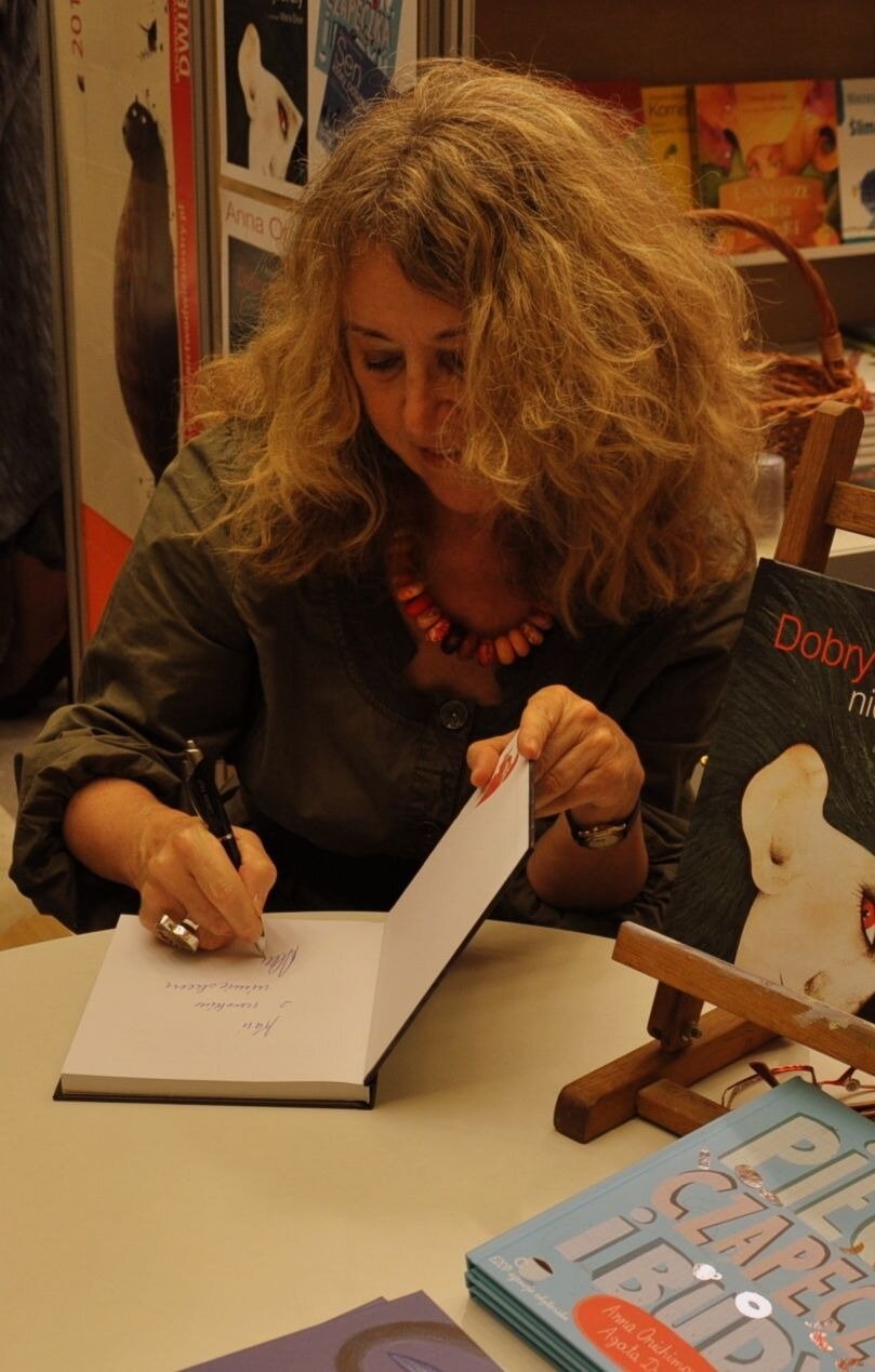 Fotografia kobiety podpisującej książkę.