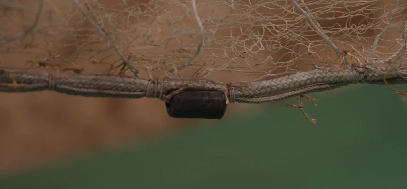 Zdjęcie przedstawia przykładowy obciążnik. Jest on zamontowany w dolnej części liny. Ma prostokątny kształt. Służy obciążeniu liny.