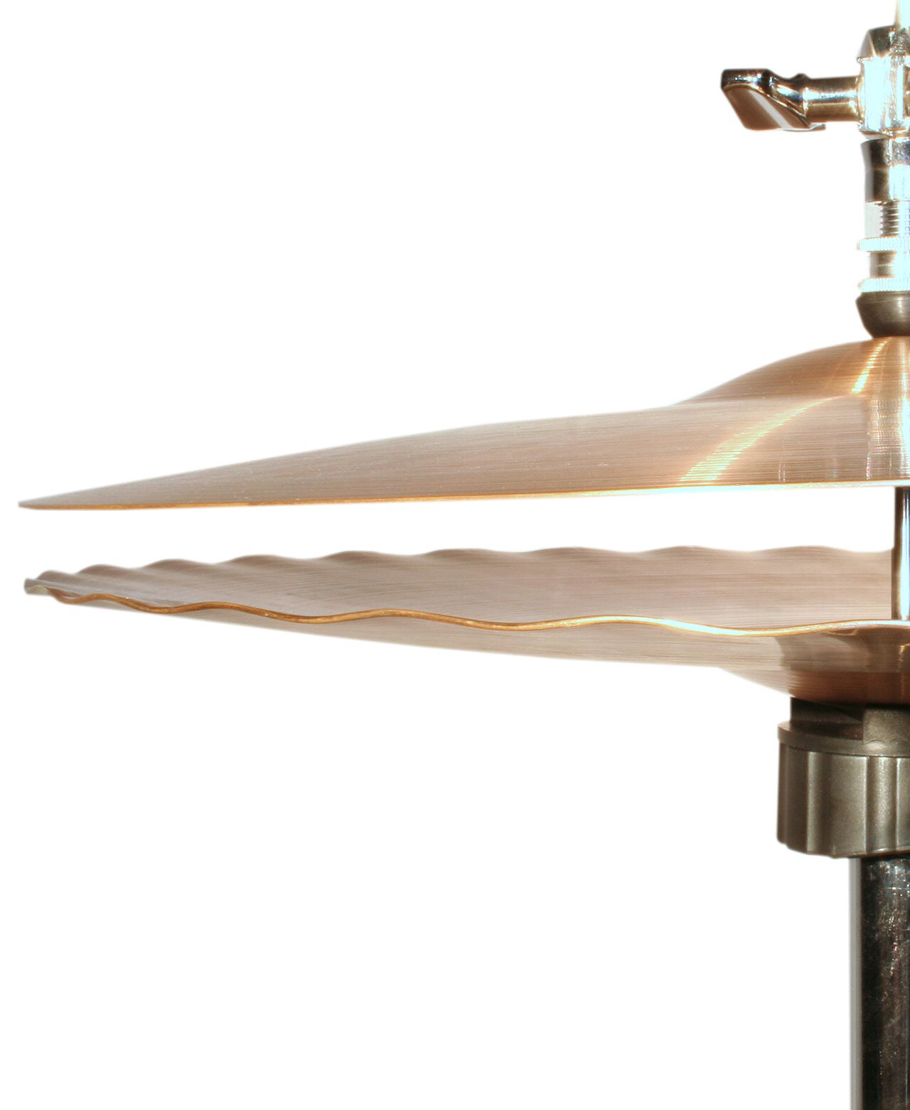 Zdjęcie przedstawia hi‑hat. Widoczna jest połowa dwóch okrągłych talerzy perkusyjnych, ustawionych w pozycji poziomej, przeciwstawnie do siebie. Górny talerz, w kolorze złotym, ma lekko wypukły, okrągły element w górnej części, na którym umieszczone jest srebrzysto‑złote pokrętło motylkowe na cylindrycznym gwincie. Dolny talerz, w kolorze złotym, ma lekko wypukły, okrągły element w dolnej części, poniżej którego znajduje się widoczny w trzech czwartych pierścień w kolorze mosiądzu, usadowiony na czarnej pionowej rurce.