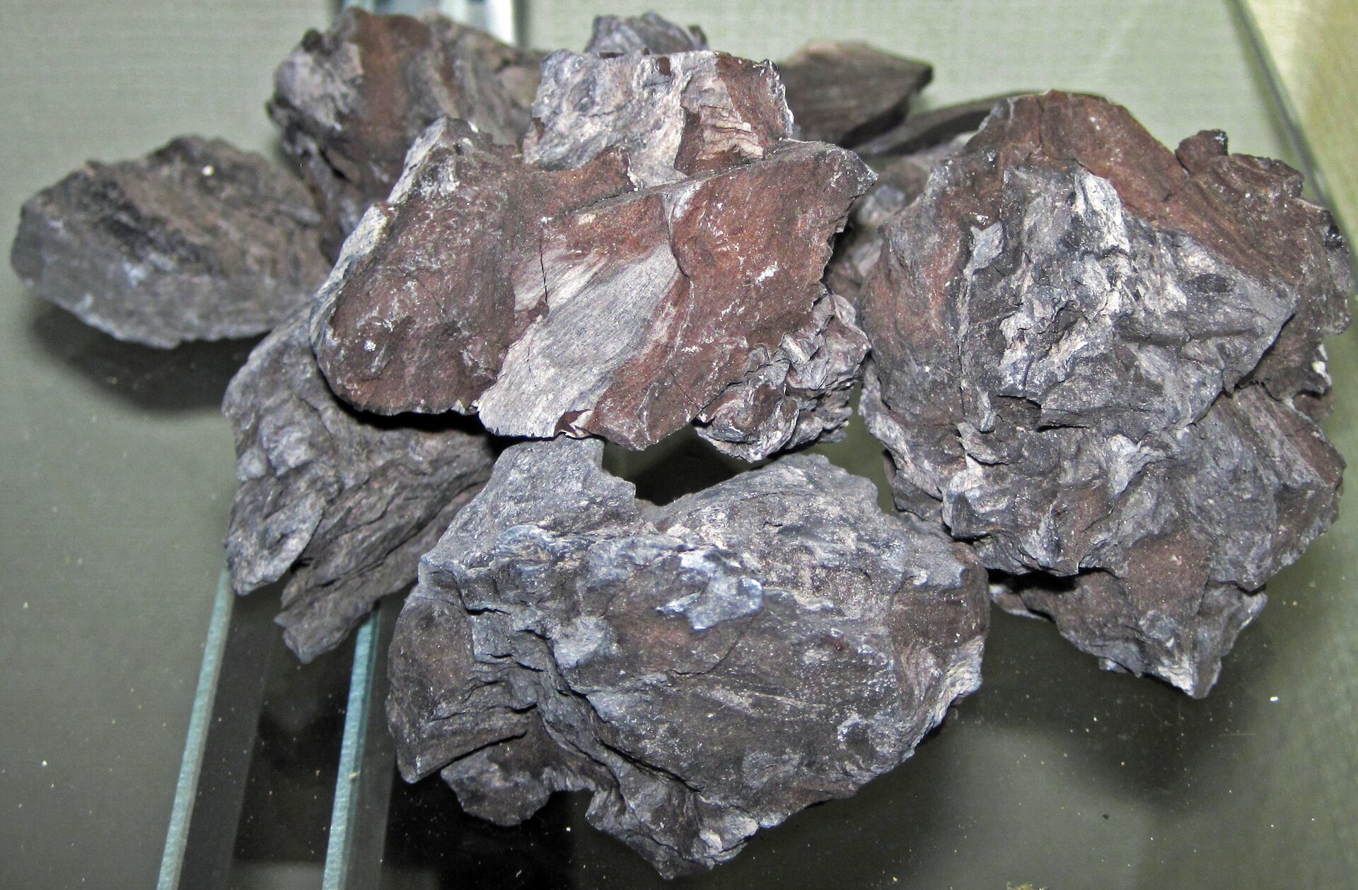 Ilustracja przedstawia czarno‑brązowe bryłki węgla brunatnego. Powierzchnia jest nieregularna, matowa.