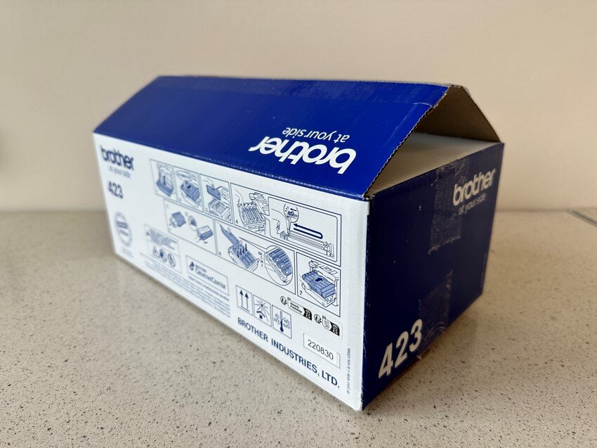 Zdjęcie przedstawia zadrukowane pudło białe z tektury faliste z górnymi skrzydełkami lekko wywiniętymi do góry.