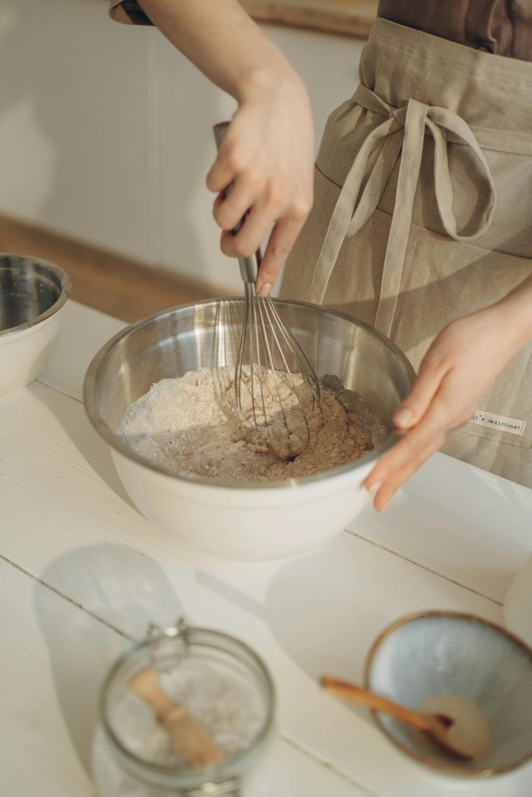 Dziesiąte zdjęcie jest podpisane Trzepaczka rózgowa. Na zdjęciu widać kobietę w brązowym fartuchu kuchennym mieszającą ciasto przy użyciu metalowej trzepaczki typu rózga w metalowej misce.