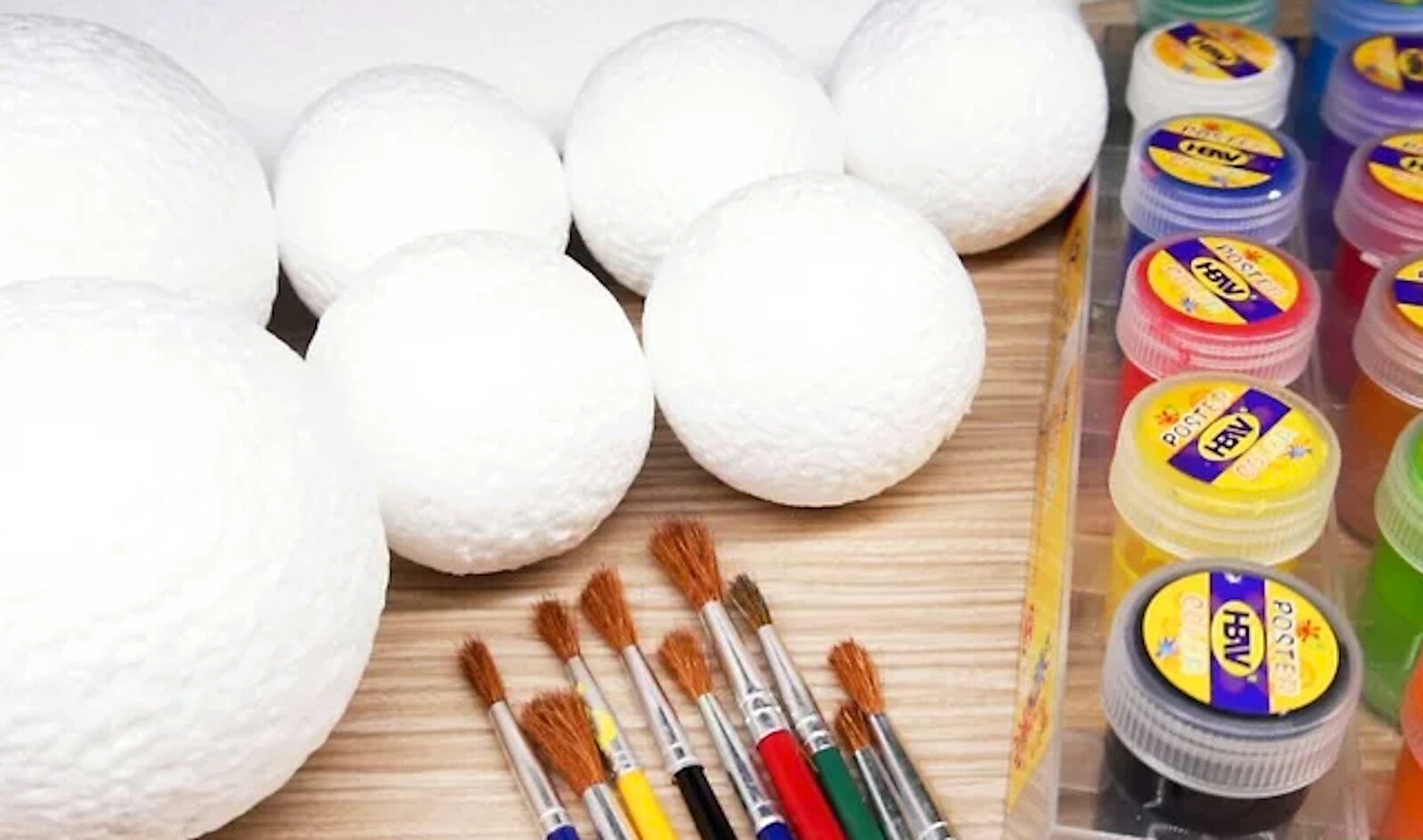 Zdjęcie przedstawia styropianowe białe kule, pędzelki i po prawej stronie są tubki z różnymi kolorami farb.