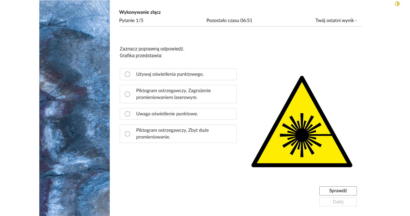 Grafika przedstawia przykładowe zadanie testowe. Ponad poleceniem widać numer pytania, czas, który pozostał na wypełnianie testu, oraz ostatni uzyskany wynik. Pod poleceniem znajdują się możliwe odpowiedzi oraz ilustracja, do której nawiązuje polecenie. W prawym dolnym rogu panelu z zadaniem znajdują się dwa przyciski. Są to "Sprawdź" oraz "Dalej".