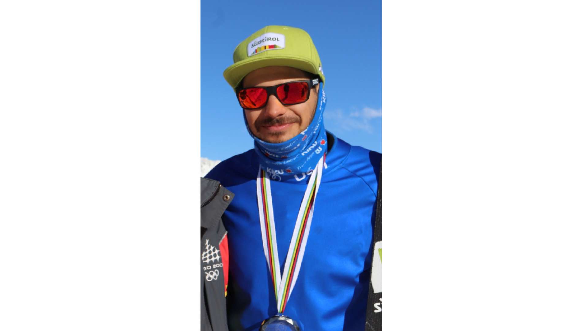 Zdjęcie przedstawia włoskiego snowboardzistę Omara Visintina z medalem na szyi. Mężczyzna nosi czapkę z daszkiem i ciemne okulary.