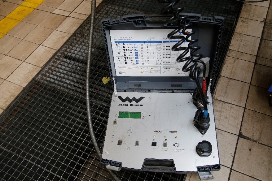 Ilustracja przedstawia tester diagnostyczny, jest to rozkładana skrzynka na jednej połowie znajduję się konsola dotykowa oraz miejsce na podłączenie kabli na drugiej tablica z opisywanymi błędami.  Tester diagnostyczny to popularne urządzenie elektroniczne, pozwalające na odczytywanie kodów błędów, kasowanie ich, na instalację nowych czujników i elementów osprzętu silnika, a także na modyfikacje oprogramowania samochodu