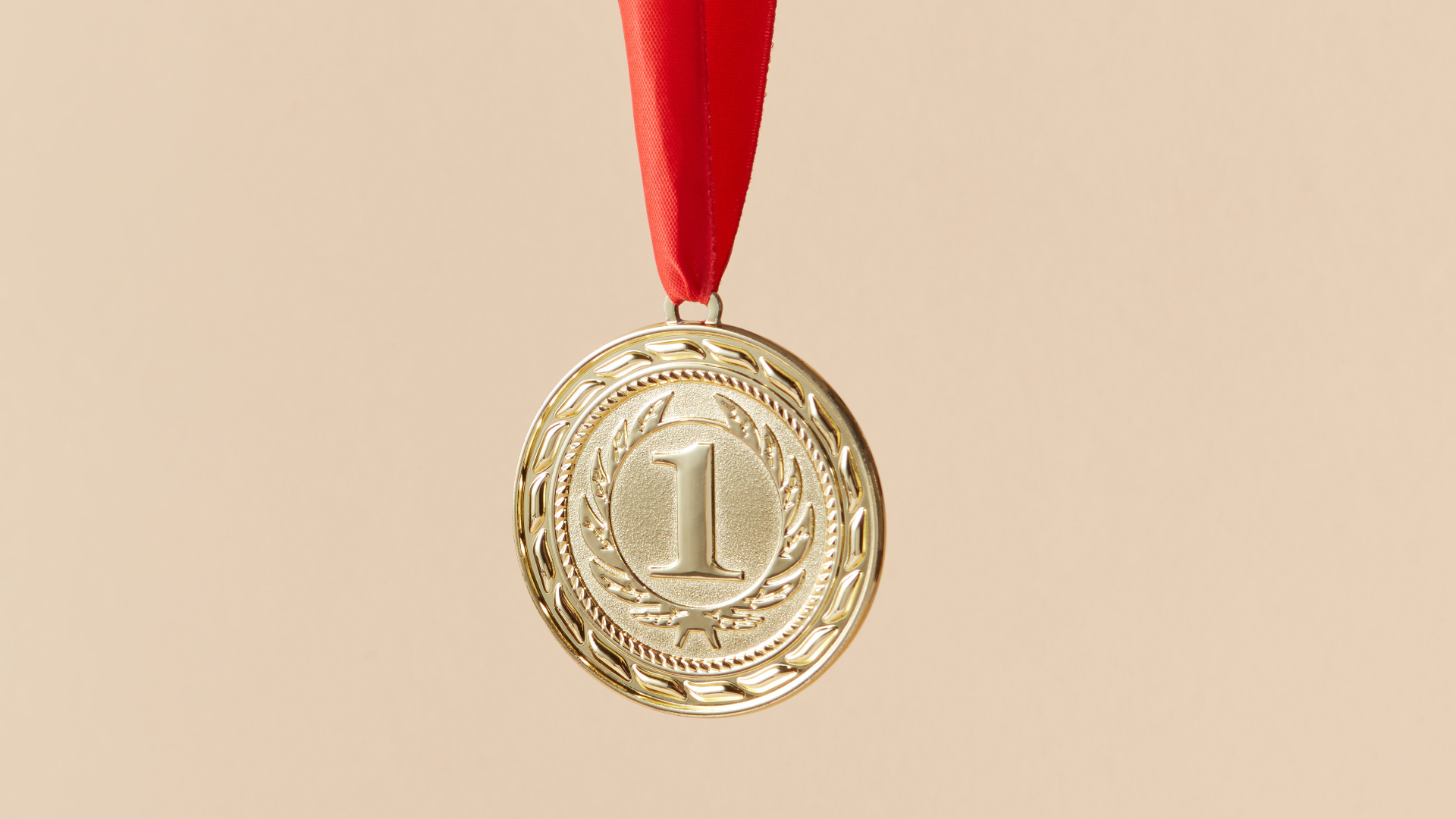 Zdjęcie przedstawia okrągły złoty medal. Na medalu jest numer 1.
