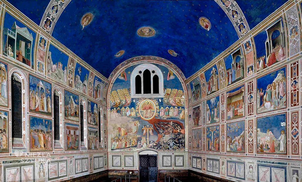 Zdjęcie obraz ukazuje wnętrze kaplicy, której sklepienie jest zaokrąglone. Ściany pomieszczenia ozdobione są kolorowymi freskami ułożonymi obok siebie po cztery w jednej linii, w których przeważa barwa niebieska. Freski przedstawiają sceny z biblii. Sufit pokryty został niebieską farbą. Znajdują się na nim okrągłe portrety.