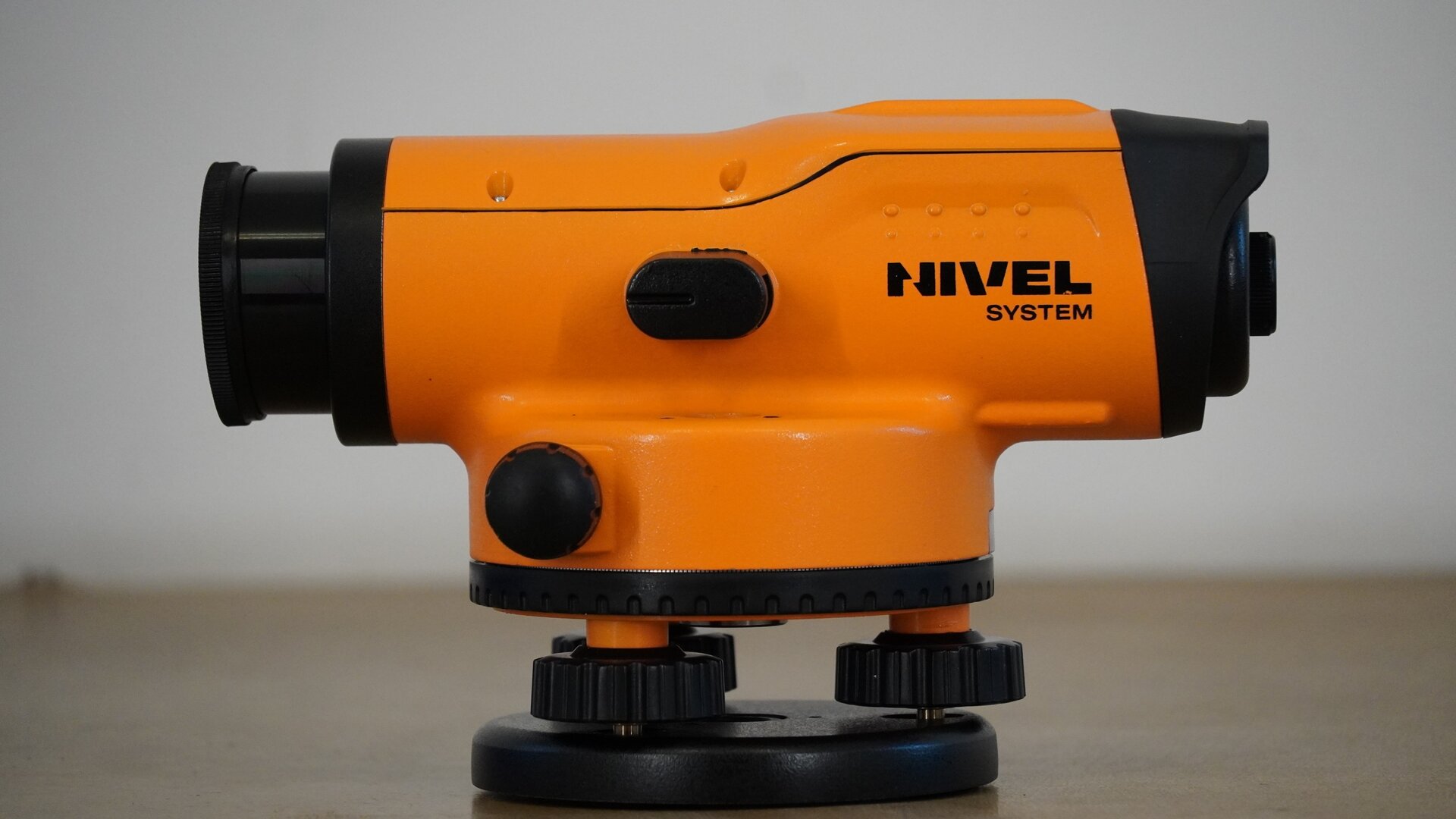 Na zdjęciu ukazano zbliżenie niwelatora ukazanego z jednego boku. Na samym dole znajduje się okrągły czarny element, to spodarka. Na niej mieszczą się trzy śruby, na nich zaś koło poziome z podziałką stanowiące dolną część okrągłego korpusu. Z boku korpusu znajduje się czarne pokrętło leniwki, a na korpusie podłużna luneta, która z jednej strony posiada węższy okular, a z drugiej – obiektyw. Z boku lunety mieści się mały owalny element, to libella.