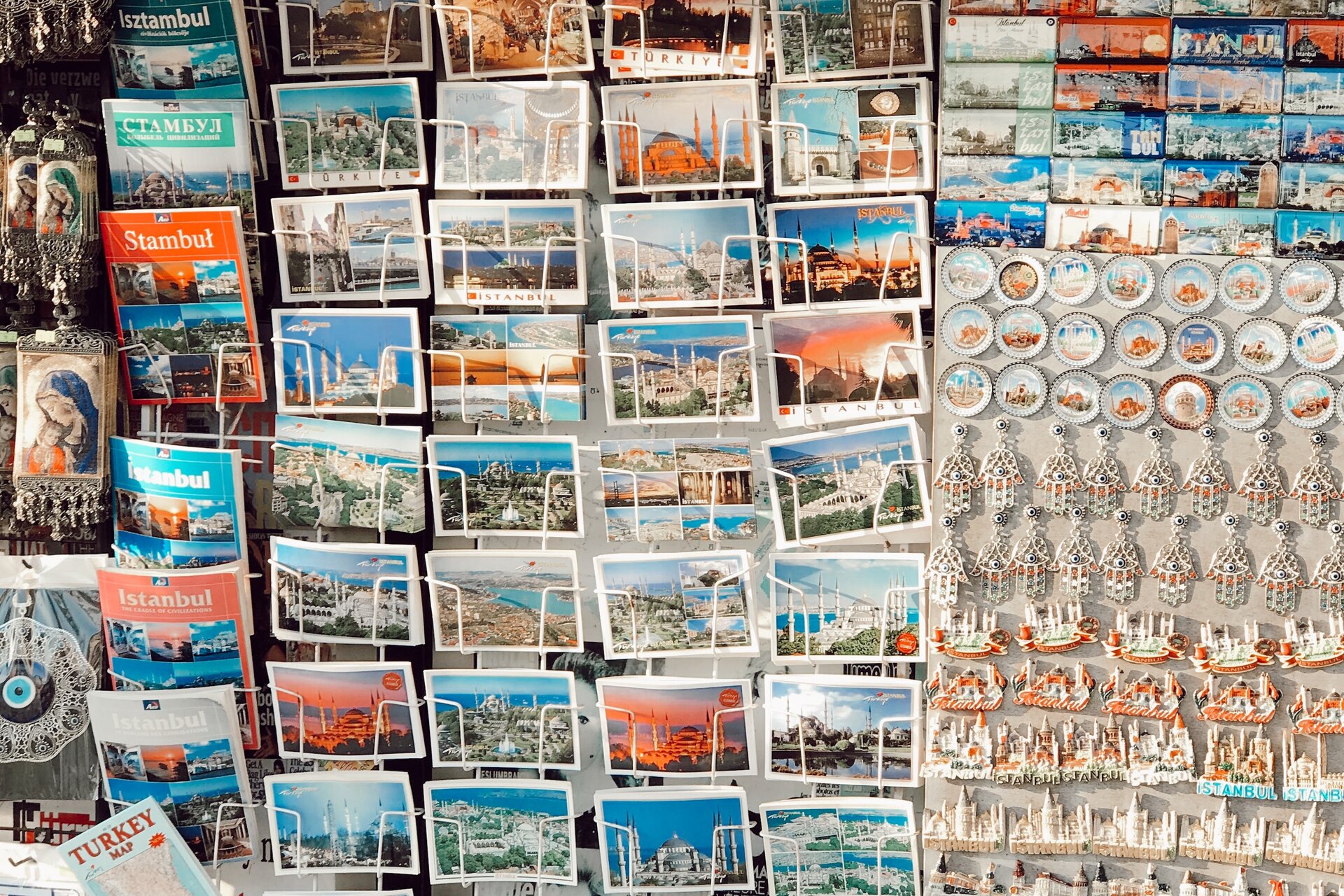 Ilustracja przedstawia stoisko z pocztówkami, magnesami i przewodnikami. 