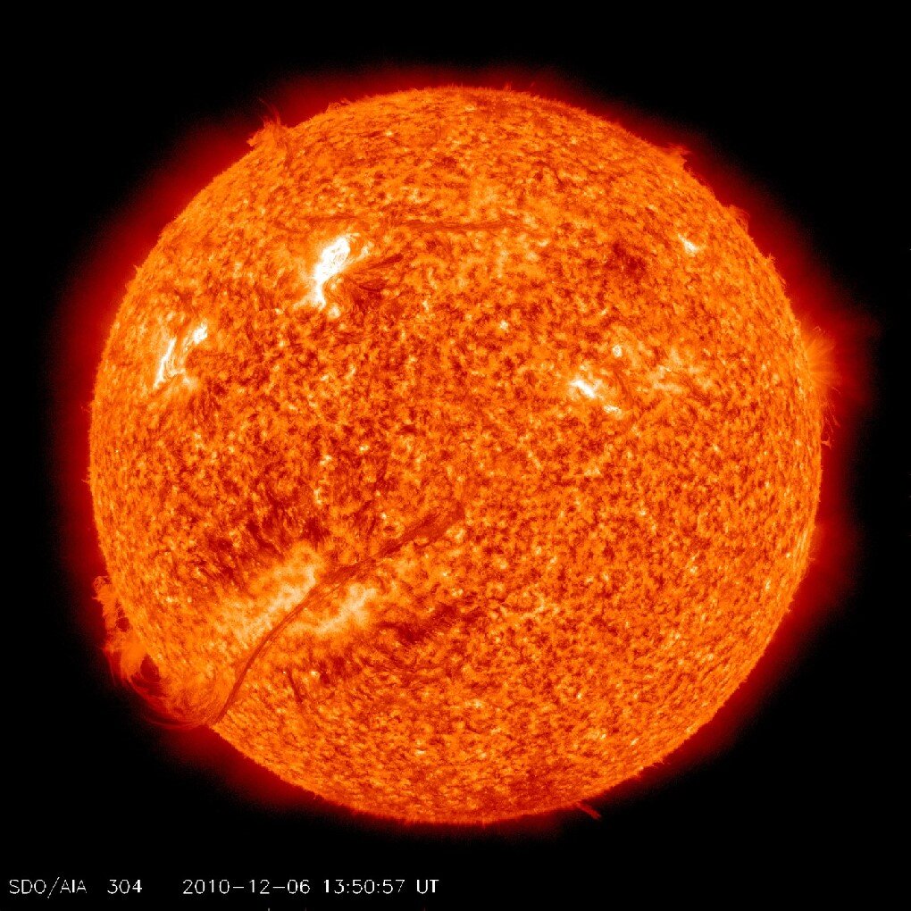 Fotografia prezentuje pomarańczowo-żółtą tarczę Słońca na czarnym tle. Słońce przypomina rozżarzoną kulę.