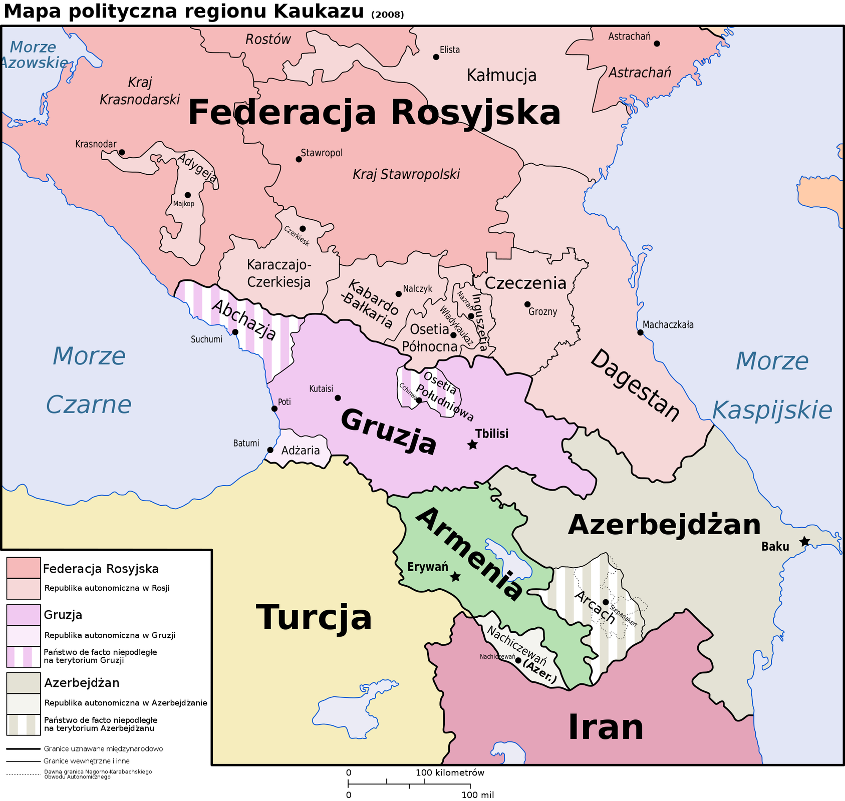 Mapa polityczna regionu Kaukazu. Kolorem różowym zaznaczono Federację Rosyjską, a kolorem jasnoróżowym republiki autonomiczne w Rosji. Są to: Adygeja, Kałmucja, Dagestan, Czeczenia, Inguszetia, Osetia Północna, Kabardo‑Bałkaria, Karaczajo‑Czerkiesja. Kolorem jasnofioletowym zaznaczono Gruzję. Pasami fioletowo‑białymi zaznaczono państwa de facto niepodległe na terytorium Gruzji. Są to: Abchazja, Osetia Południowa. Kolorem białym zaznaczono republikę autonomiczną Gruzji, jest to Adżaria. Kolorem szarym zaznaczono Azerbejdżan. Szaro‑białymi pasami zaznaczono państwo de facto niepodległe na terytorium Azerbejdżanu, jest to Arcach. Kolorem jasnoszarym zaznaczono republikę autonomiczną Azerbejdżanu, jest to Nachiczewań.