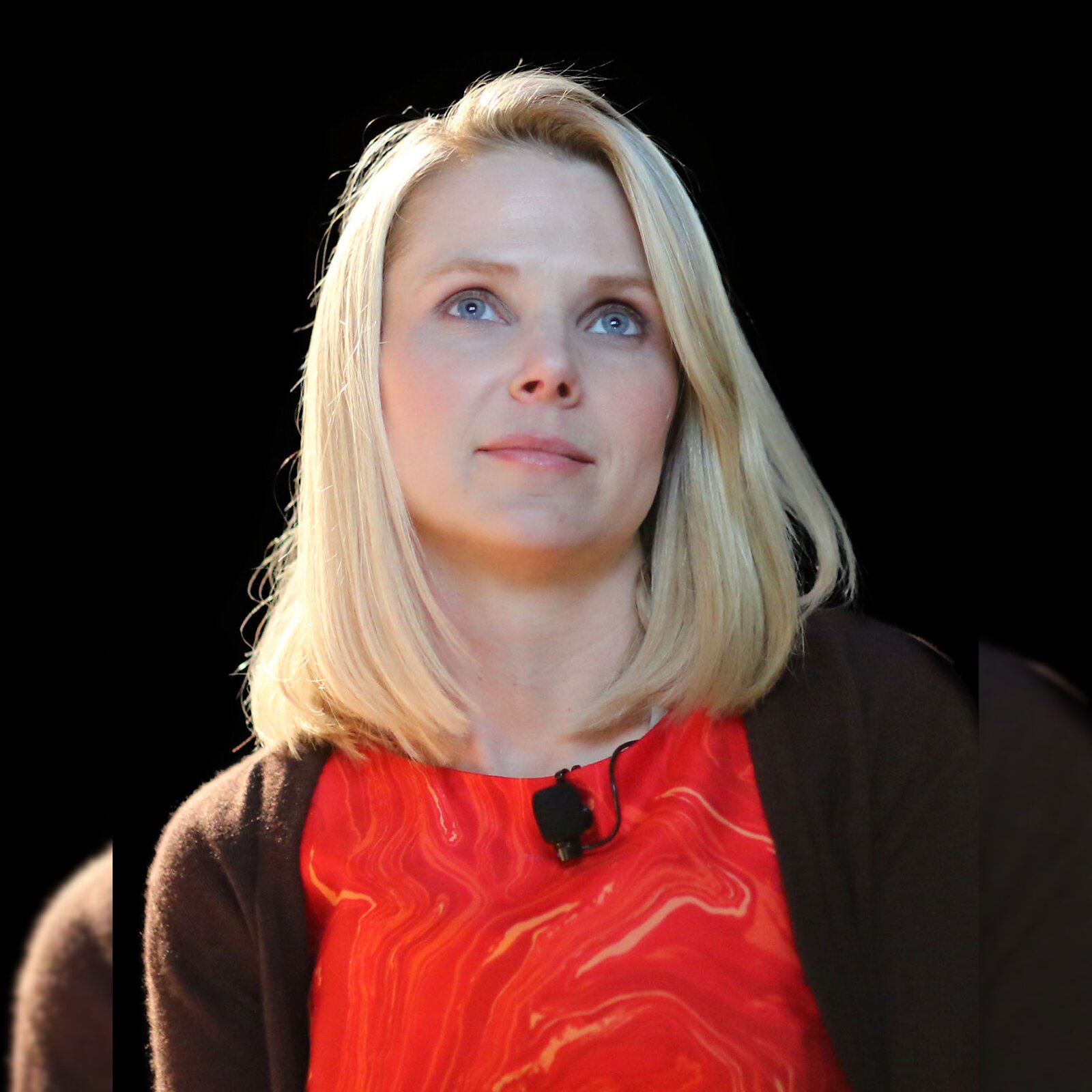 Zdjęcie przedstawia młodą kobietę. Kobieta ma mały nos, niebieskie oczy i blond włosy do ramion. Ubrana jest w czerwona bluzkę i brązowy sweter.