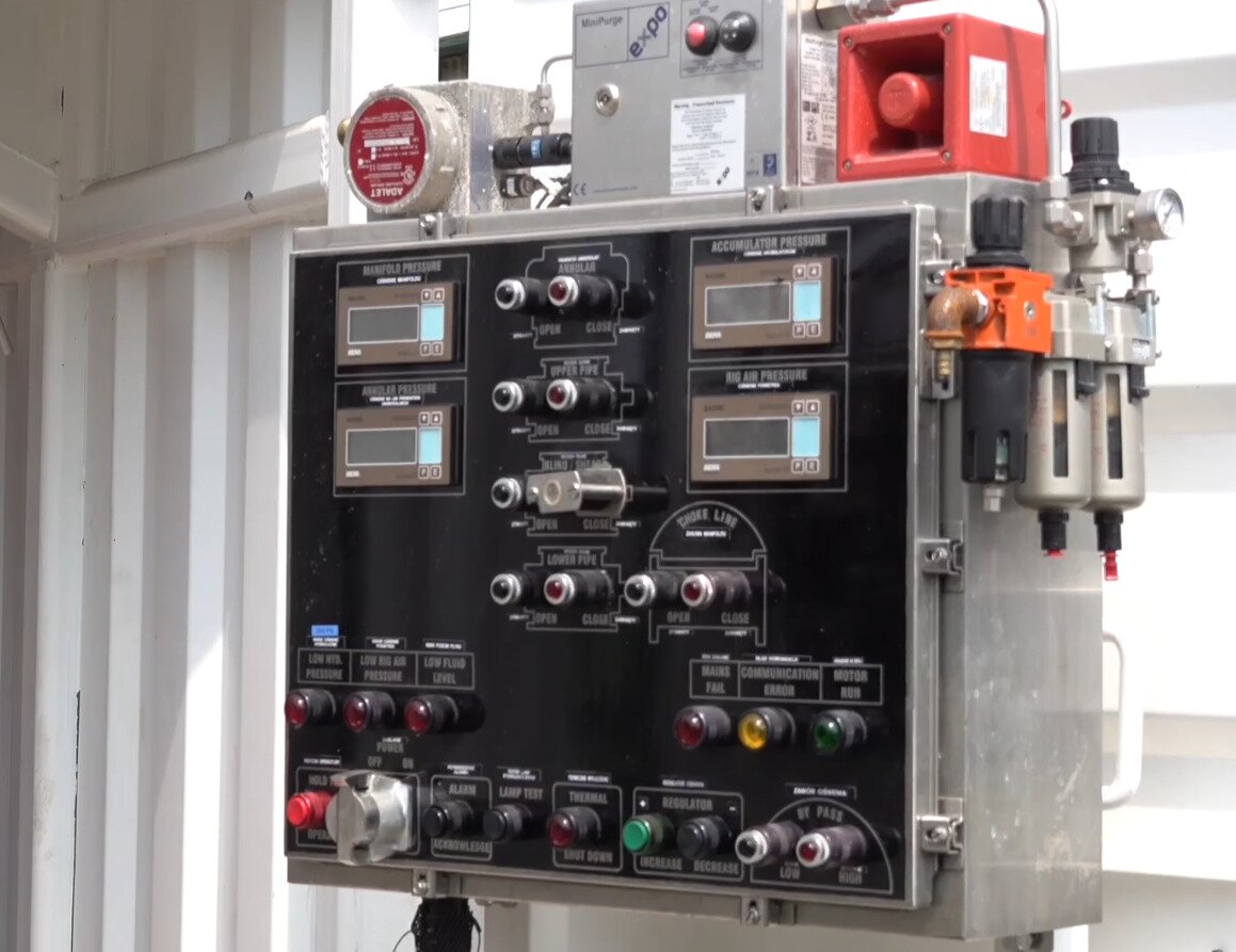 Na zdjęciu widoczna jest sterowania zabezpieczenia przeciwerupcyjnego. Sterownia jest w fomie prostopadłościennej skrzynki  wykonanej z metalowej obudowy. Na przodzie skrzyni znajdują się przełącznik, oraz cztery niewielkie ekrany. Na dole sterowni widać dziewięć przełączników. Powyżej po każdej stronie znajduje się po trzy kolorowe guziki. W środkowej części sterowni widocznych jest osiem przyciski są rozłożone po cztery w dwóch kolumnach. Obok przycisków, po obu stronach znajdują się dwa niewielkie ekrany. Nad ekranami z prawej strony znajdują się dodatkowe przyciski. Nad każdym przyciskiem umieszczona jest niewielka tabliczka z nazwą.Na boku obudowy znajduje się urządzenie z okrągłym wskaźnikiem. Na górze obudowy widoczne są trzy sześciennej urządzenia. Urządzenie po lewej przypomina wodomierz. Urządzenie po środku ma dwa przyciski. Zielony i Czerwony. Urządzenie po prawej przypomina sześcian z wyciętą ścianą boczną. W jej miejscy znajduje się poziomy walec.Poniżej zdjęcia w prawym dolnym rogu widoczny jest przycisk odtwarzania. Tekst nagrania jest zgodny z tytułem zdjęcia.