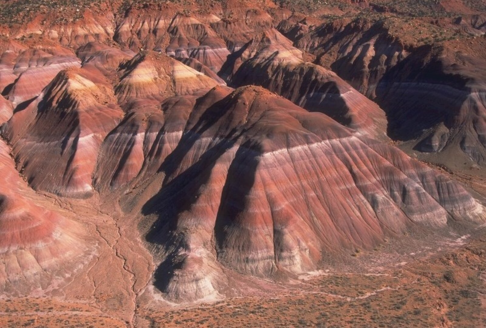Na zdjęciu tereny górzyste, pokryte rdzawym piaskowcem wokół gdzieniegdzie kępy traw.