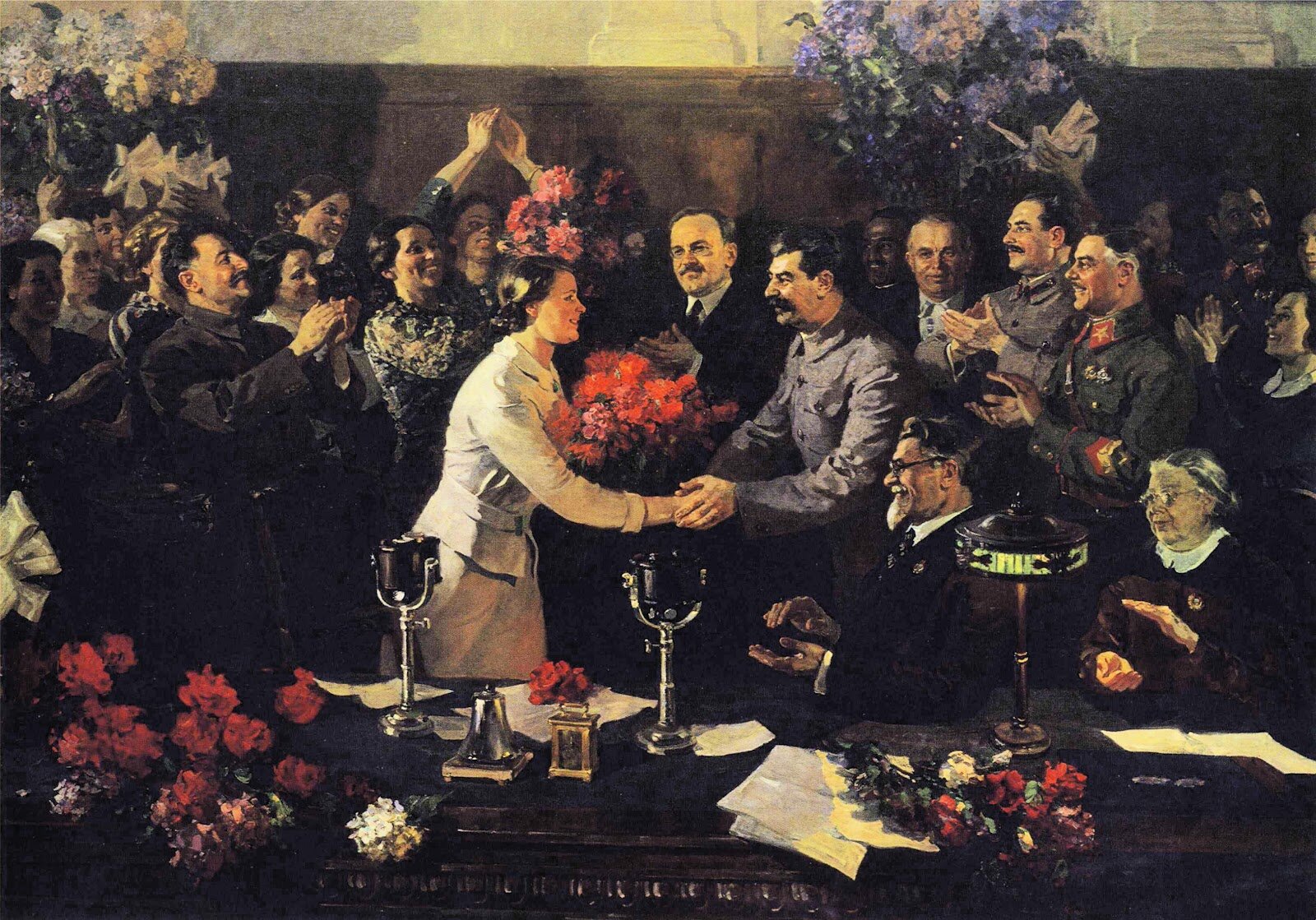 Obraz przedstawiający moment uścisku dłoni pomiędzy kobietą a Józefem Stalinem. W tle mnóstwo osób przyglądających się wydarzeniu.