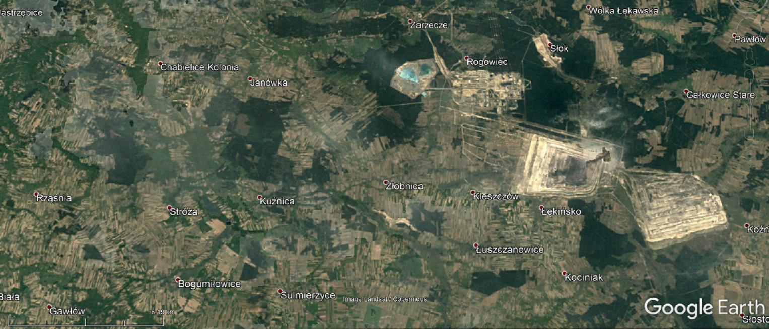 Na zdjęciu satelitarnym jest krajobraz, na którym po prawej stronie są dwa jasnożółte kwadraty. Jeden z nich jest niewysokim wzniesieniem. Na północny zachód od nich jest zbiornik zaznaczony kolorem turkusowym. Zagłębie jest pomiędzy miejscowościami: Kleszczów, Rogowiec, Łękińsko.  