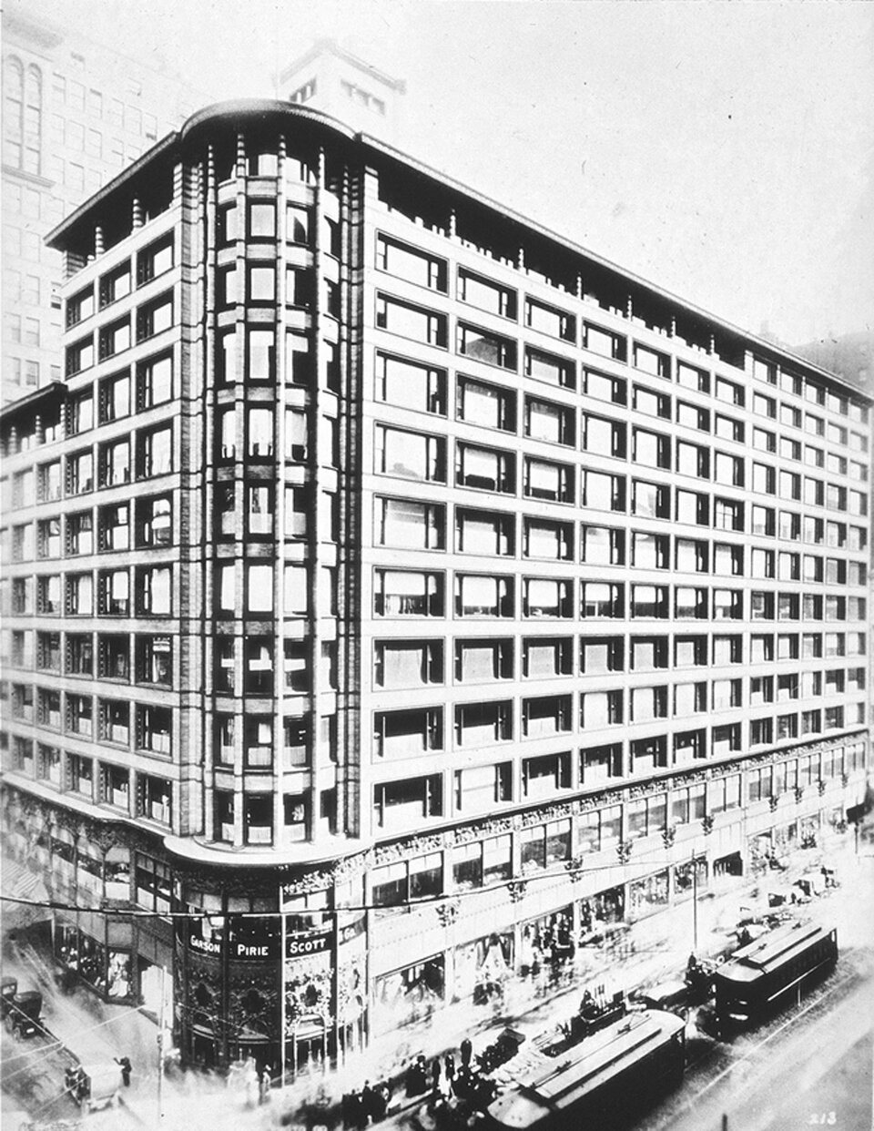 Ilustracja przedstawia widok zewnętrzny na Sullivan Center w Chicago. Budynek jest niezwykły ze względu na konstrukcję z ramą stalową, która pozwoliła na gwałtowny wzrost powierzchni okien utworzonych przez szerokie okna wnękowe, co z kolei pozwoliło na uzyskanie największej ilości światła dziennego we wnętrzach budynku. Pomiędzy oknami były pasma terakoty, zastępujące wcześniejszy plan białego marmuru z Gruzji. Projekt obejmował brązowane żeliwne prace ozdobne nad zaokrągloną wieżą.