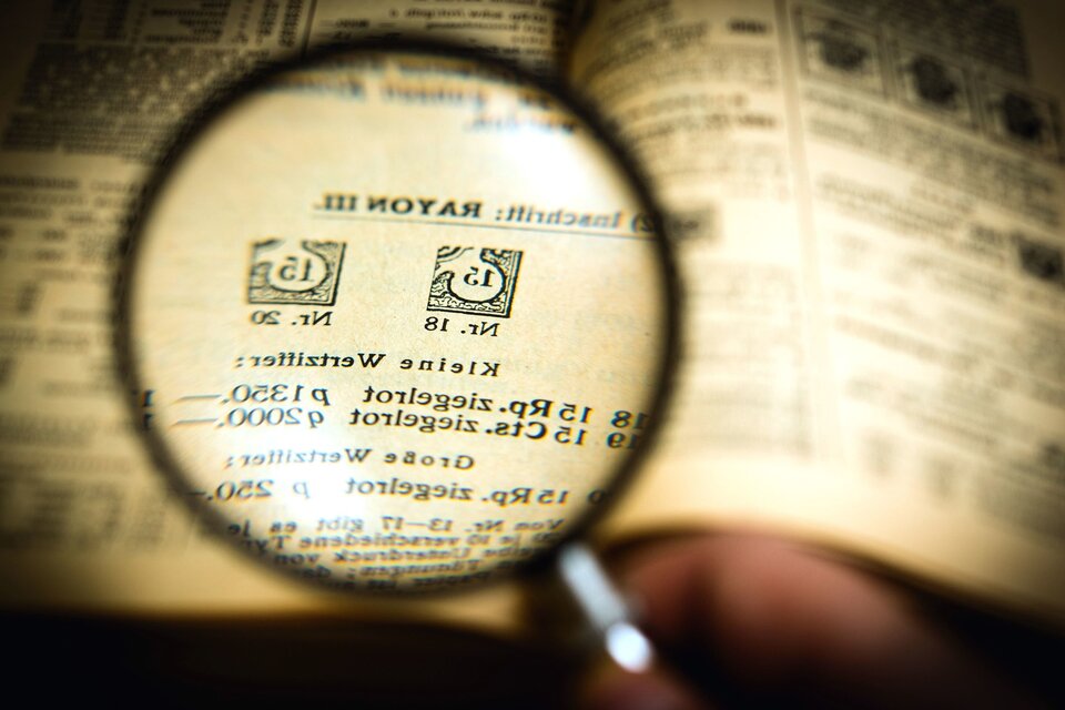 Ilustracja przedstawia lupę, która powiększa zapis umieszczony w pewnej książce.