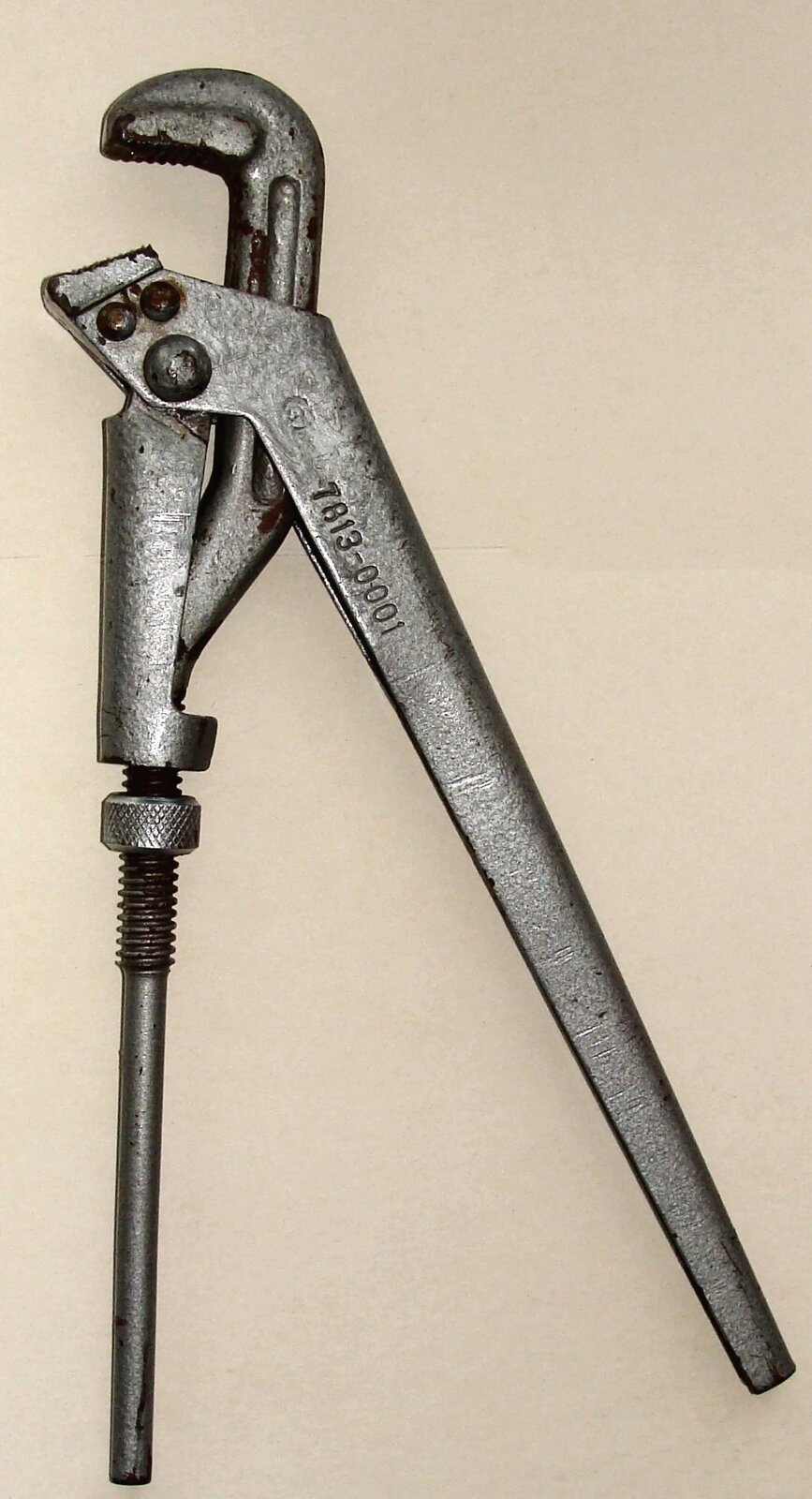 Zdjęcie przedstawia stalowy klucz. Składa się z dwóch długich rękojeści zakończonych tak zwaną szczęką. Pod nią znajduje się śruba służąca do regulacji zacisku.