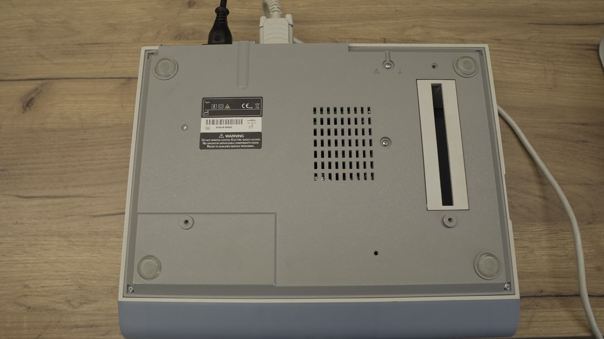 Zdjęcie przedstawia spód spirometru. Widoczne są nóżki umieszczone w czterech rogach obudowy oraz tabliczka znamionowa.