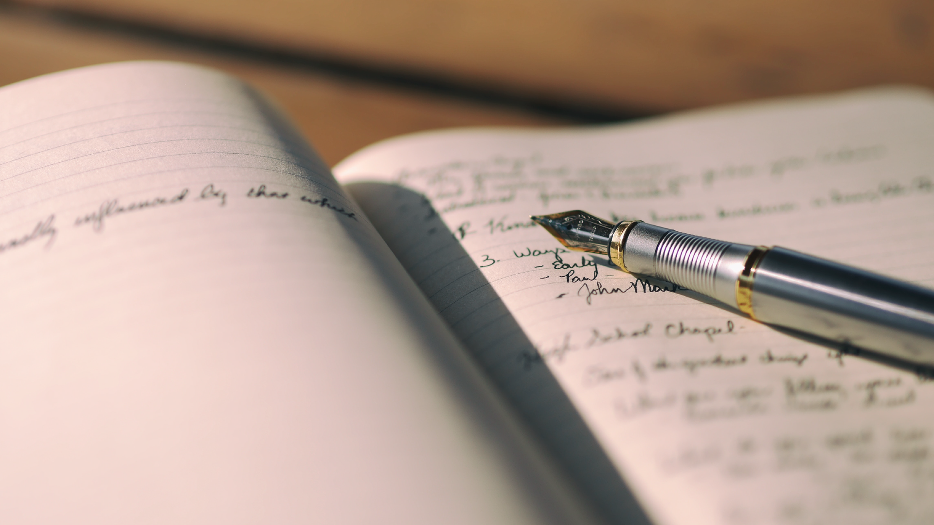Zdjęcie przedstawia otwarty notes z zapiskami. Po prawej stronie notesu leży pióro.