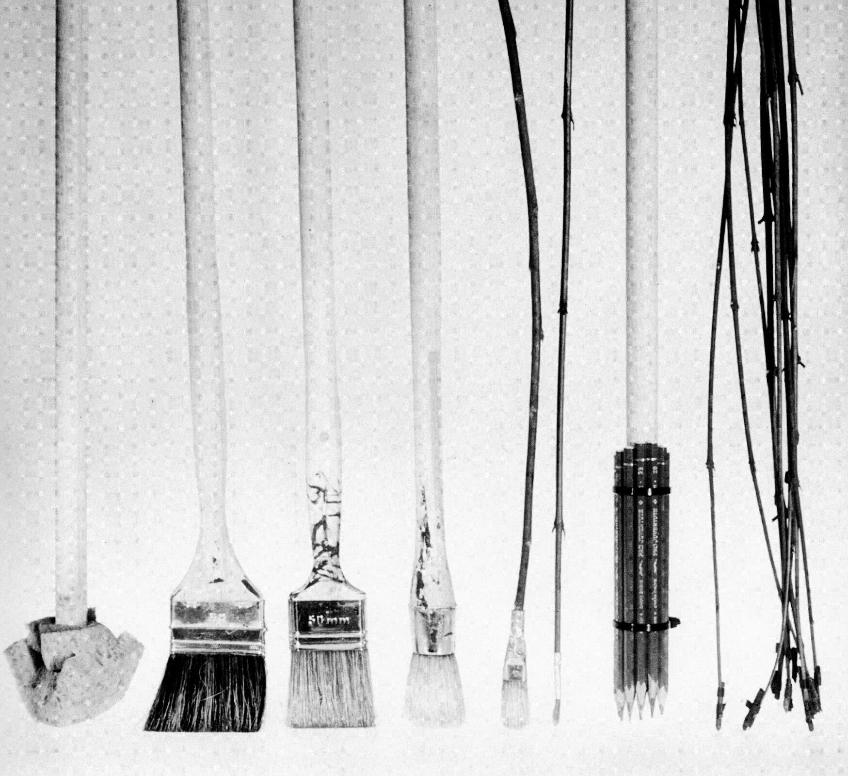 Czarno - biała ilustracja przedstawia różne narzędzia rysunkowe ułożone pionowo jedno obok drugiego. Od lewej: gąbka na patyku, pędzel płaski do kaloryferów, pędzel płaski, pędzel okrągły, pędzel okrągły o połowę mniejszy od poprzedniego,  bardzo mały pędzelek okrągły na cienkim patyczku, kilka ołówków zawiązanych razem na patyku, piórka zamontowane na cienkich gałązkach.