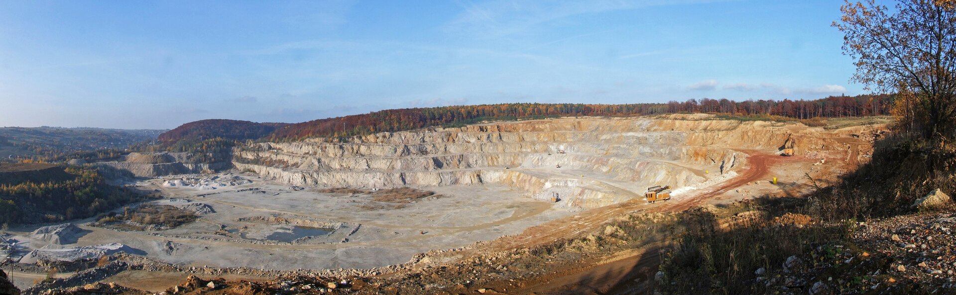Zdjęcie przedstawia kamieniołom. To kopalnia odkrywkowa. Dół kamieniołomu jest płaski, otaczają go odkryte, pionowe bloki skalne przypominające schody.