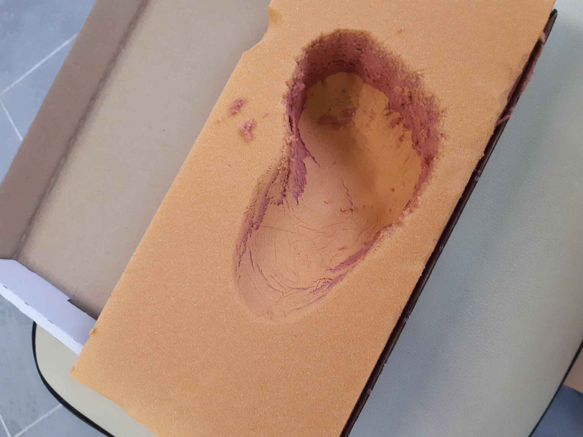 Zdjęcie przedstawia wycisk kształtu dziecięcej stopy w piance widzianej od góry.