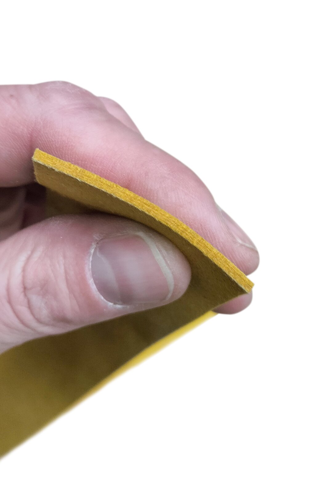 Zdjęcie przedstawia skórkę jelonkową. Widoczny jest prostokątny płat skórki w kolorze żółtym, trzymany w dłoni za koniec skórki w celu zaprezentowania jej przekroju.