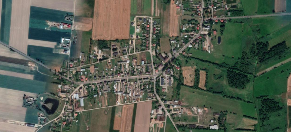 Zdjęcie wykonane z góry ukazuje płaski teren z licznymi polami. Przy ulicach stoją liczne zabudowania. Ulice biegną w różnych kierunkach, w części centralnej tworzą kształt prostokątny. 