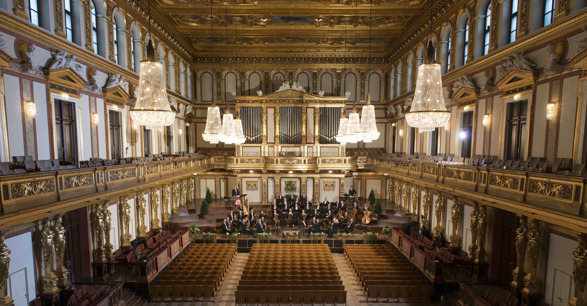 Ilustracja przedstawia słynną salę koncertową Großer Musikvereinssaal – Goldener Saal. Na końcu pomieszczenia znajdują się miejsca dla muzyków, przed nimi są miejsca dla widzów.