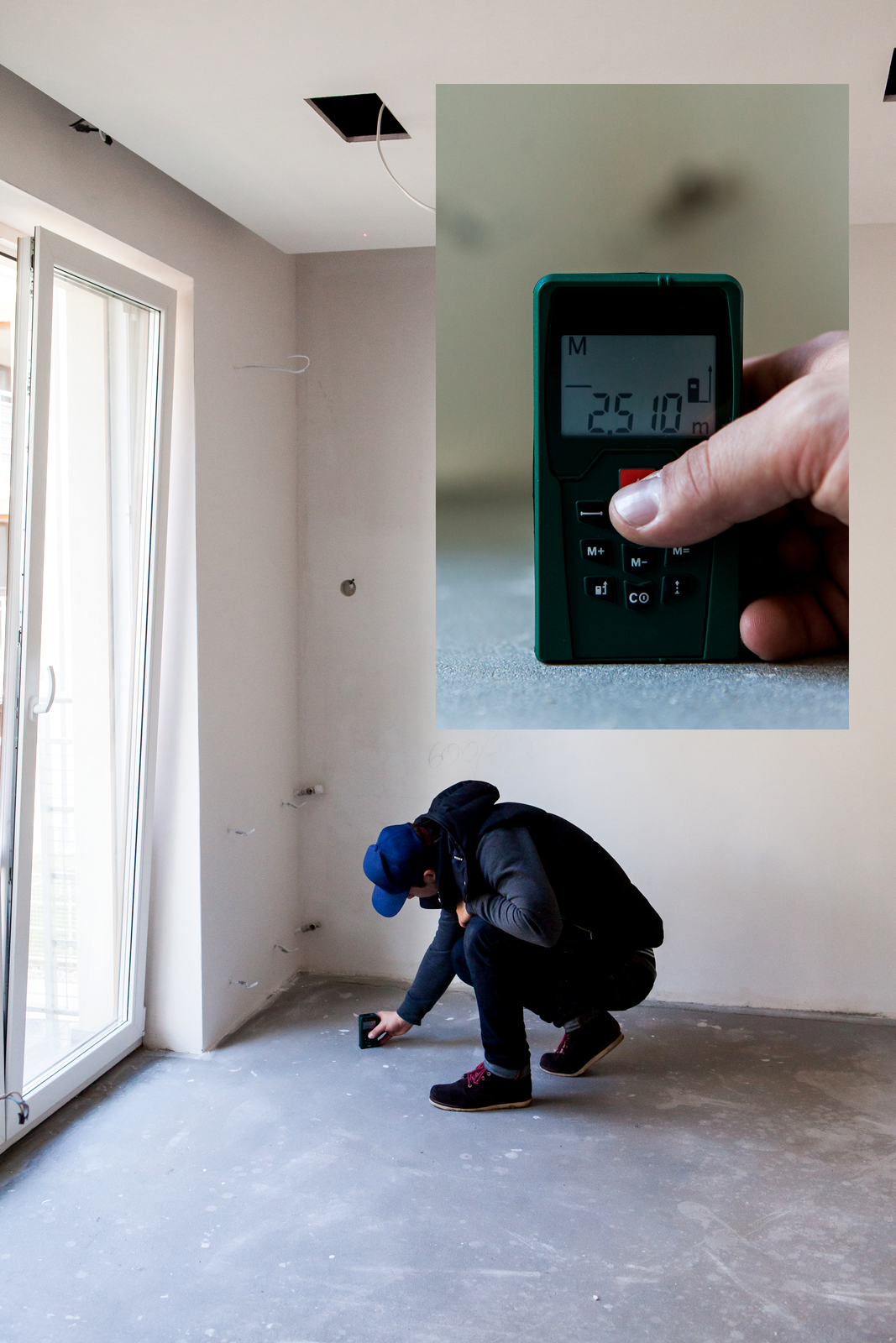 Zdjęcie przedstawiające osobę dokonującą pomiaru pomieszczenia za pomocą dalmierza. Na tle jasnych ścian widać schyloną osobę trzymającą przedmiot w kształcie pudełka. W rogu zdjęcia powiększenie wyświetlacza przyrządu. Widać czarne pudełko z szybką przezroczystą, za którą widać wynik pomiaru w metrach.