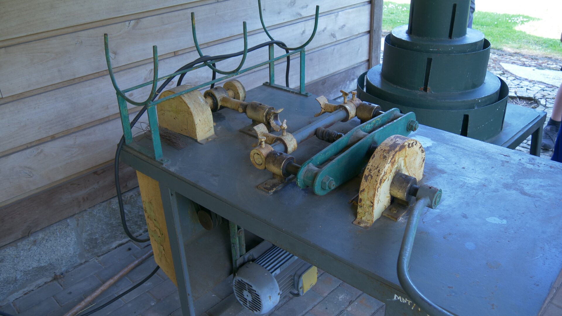 Zdjęcie przedstawia prostowarkę do kijów. Składa się ona z blatu, mechanizmu prostującego i silnika.
