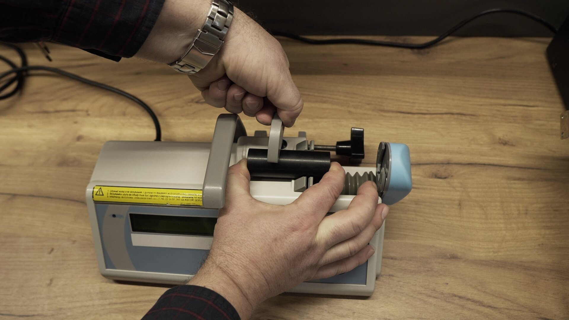 Na zdjęciu technik przeprowadza test docisku strzykawki pompy infuzyjnej. Sprawdza, czy strzykawka prawidłowo się zamyka.