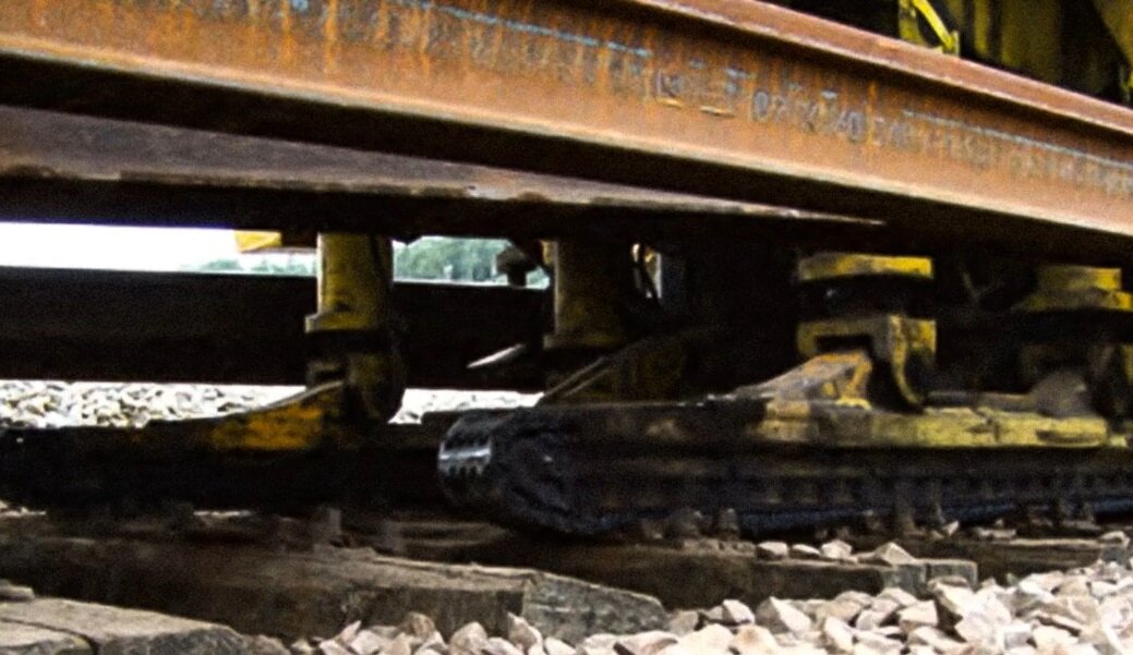 Ilustracja przedstawia sanie gąsienicowe. Na ekranie przedstawiono dwie mniejsze gąsienice maszyny znajdujące się pod szynami.