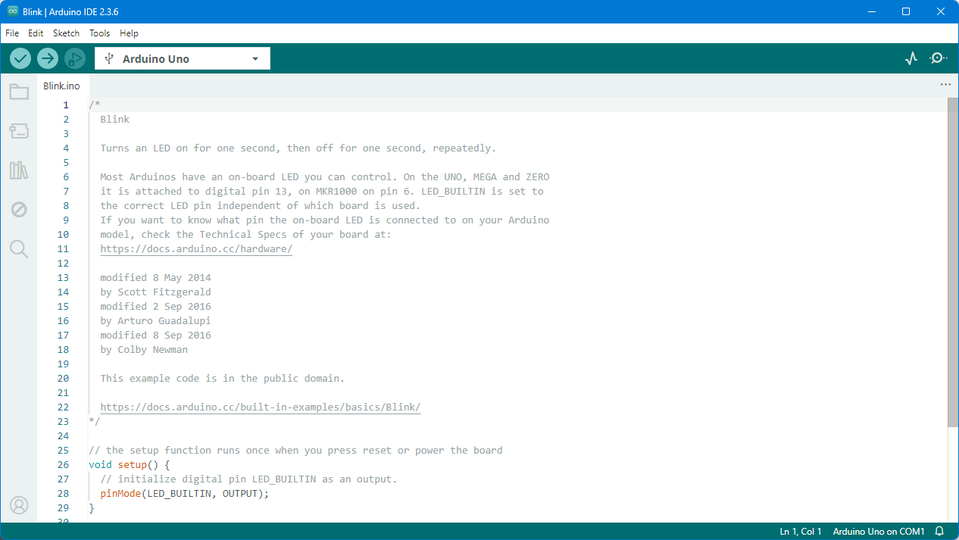 Na zrzucie ekranu widać otwarte środowisko Arduino z przykładowym szkicem „Blink.ino”. W edytorze kodu widoczny jest komentarz opisujący działanie programu — miganie wbudowaną diodą LED — wraz z instrukcjami dotyczącymi obsługi różnych modeli Arduino oraz odnośnikiem do strony z dokumentacją sprzętu. Poniżej znajduje się fragment kodu w języku C++ inicjujący tryb wyjścia dla pinu LED_BUILTIN. W nagłówku programu wybrana jest płytka „Arduino Uno”, a w prawym dolnym rogu pasku statusu widnieje informacja „Arduino Uno on COM1”.