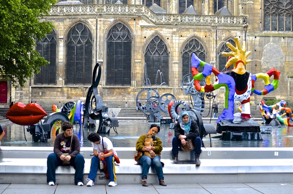 Ilustracja przedstawia pracę Niki de Saint Phalle oraz Jeana Tinguely „Fontanna Strawińskiego”. Dzieło pochodzi z 1983 roku. Obecnie możemy je znaleźć w Paryżu we Francji. Na fotografii widzimy fontannę. Zamieszczone są na niej przedmioty o różnych kształtach m.in. usta, nuty. W tle widoczne są budynki. Na fontannie siedzi kilkoro ludzi.