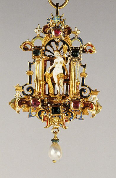 Kolorowe zdjęcie przedstawia wisiorek pochodzący prawdopodobnie z czasów baroku, zrobiony jest ze złota i drogich kamieni. Ma kształt obrazka z bogato zdobionymi ramami, w środku wisiorka umieszczono nagą, białą postać kobiety, która trzyma złotą szarfę i złoty liść. Na dole wisiorka umieszczono dużą perłę. 