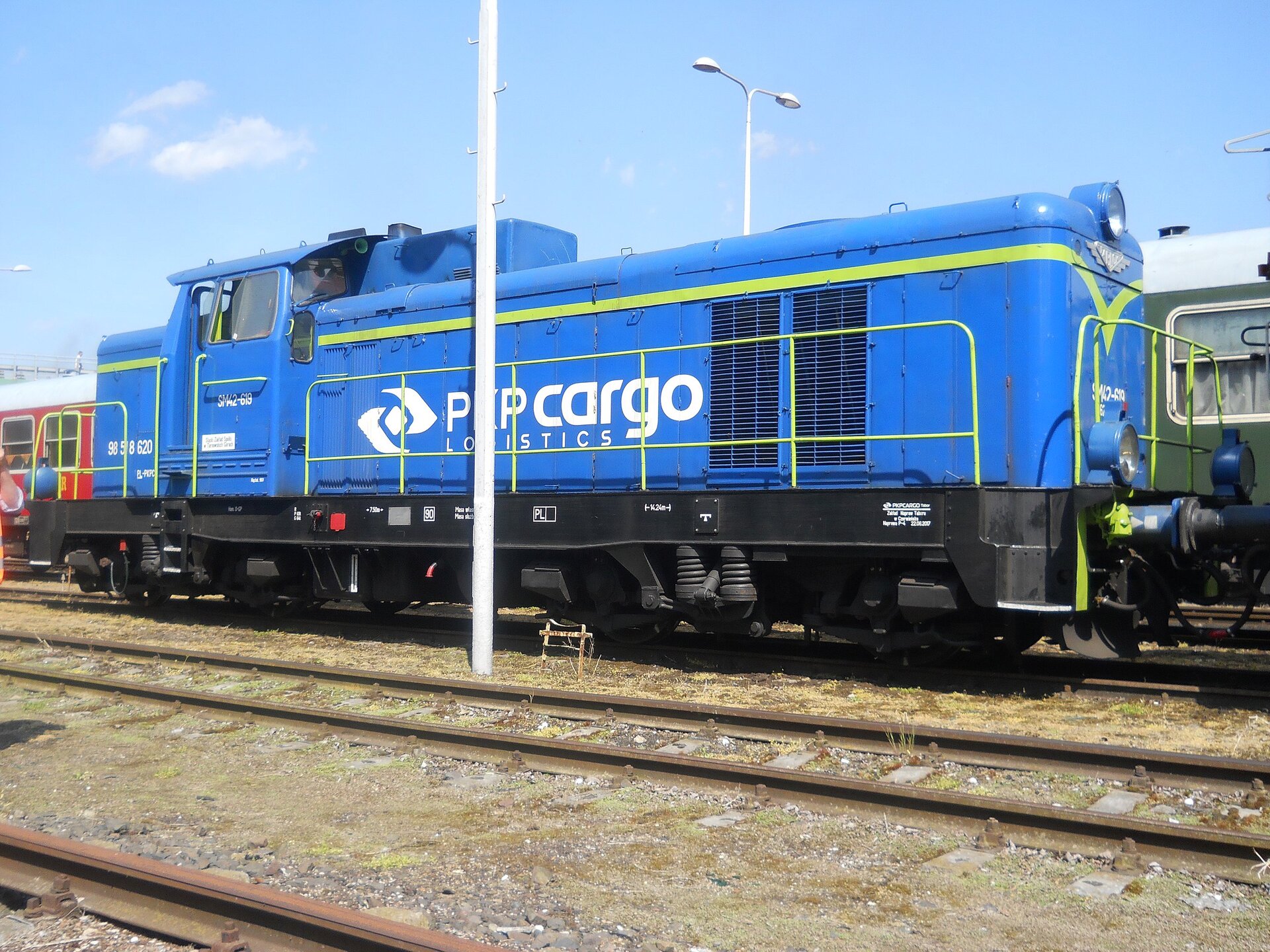 Zdjęcie przedstawia lokomotywę manewrową eS eM czterdzieści dwa. W jednej czwartej długości lokomotywy znajduje się kabina. Wzdłuż lokomotywy jest zabezpieczony balustradą pomost dla załogi.