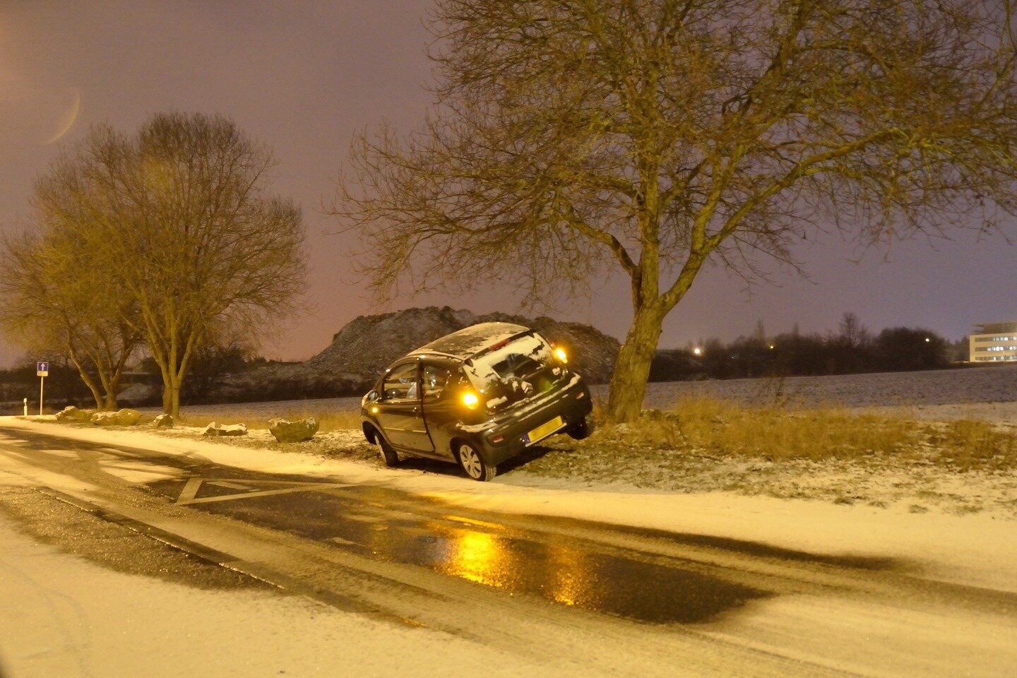 Zdjęcie przedstawia skutki gołoledzi. Widać samochód leżący w rowie. Jezdnia pokryta śniegiem i lodem.