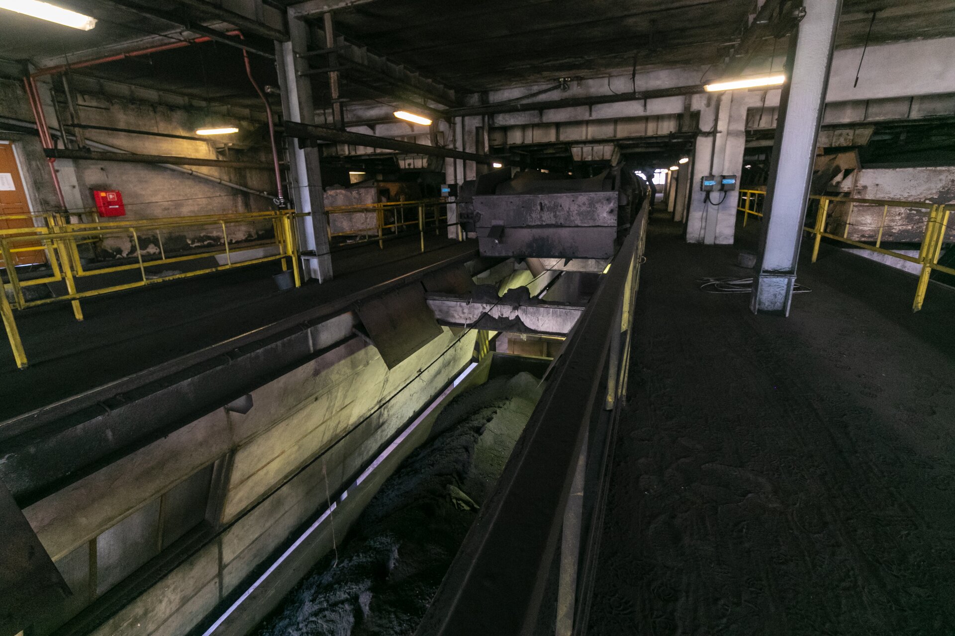 Na zdjęciu widoczna jest ładowarka węgla na wagony. Na zdjęciu widoczne jest wnętrze budynku przemysłowego. W centralnej części budynku znajduje się otwór. Przypomina on kanał u mechanika. Pod otworem stoi wagon towarowy. Wagon jest załadowany drobnoziarnistym węglem. Nad pustym wagonem widoczne jest duże czarne urządzenie o kształcie przypominającym walec.Poniżej zdjęcia widoczny jest przycisk multimedialny z nagraniem audio. Treść nagrania jest zgodna z tytułem zdjęcia.